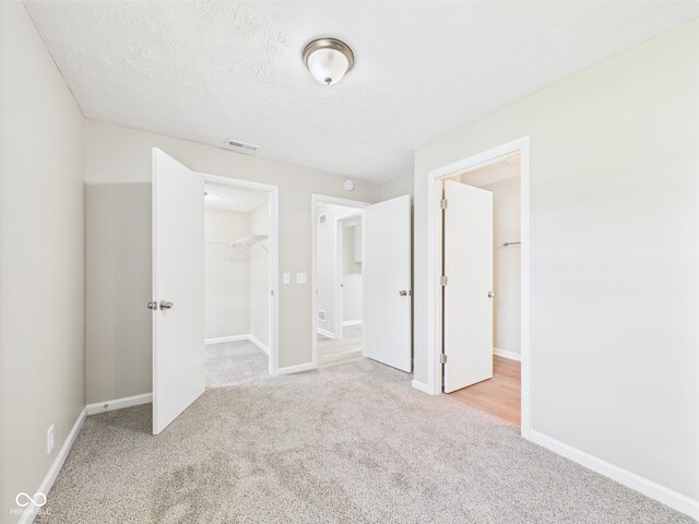 unfurnished bedroom with visible vents, baseboards, carpet floors, and a walk in closet