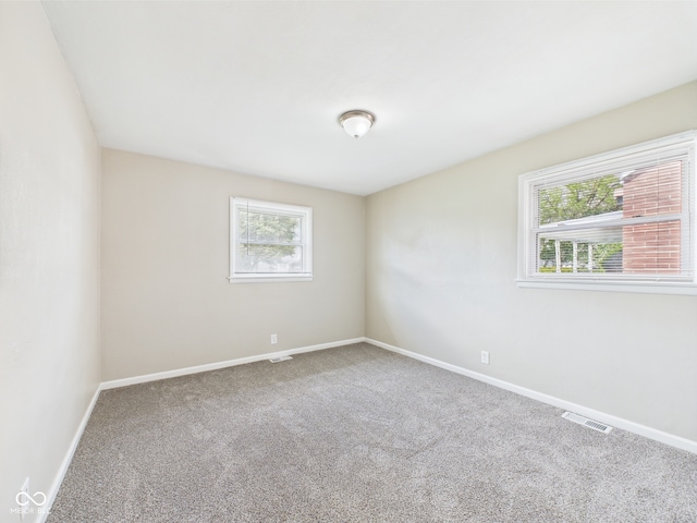 carpeted empty room with baseboards, plenty of natural light, and visible vents