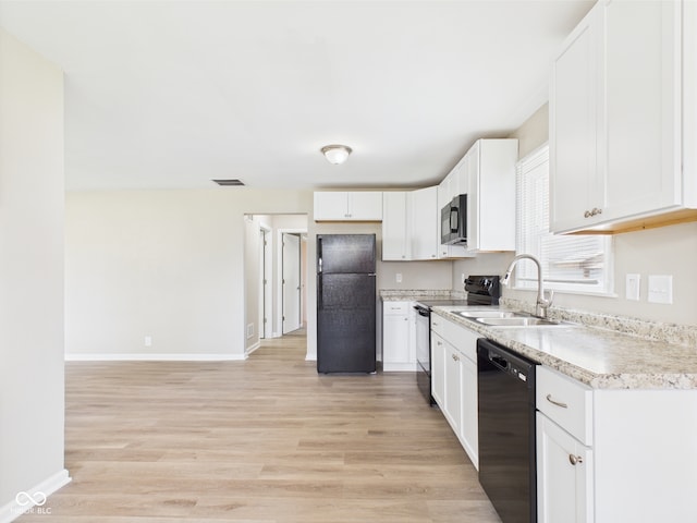 kitchen with visible vents, a sink, black appliances, and light wood-type flooring