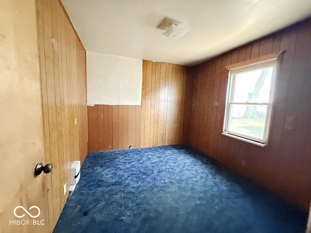 carpeted spare room with wooden walls