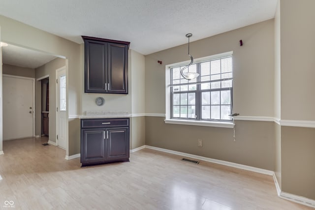 kitchen featuring baseboards, a textured ceiling, and light wood-style flooring