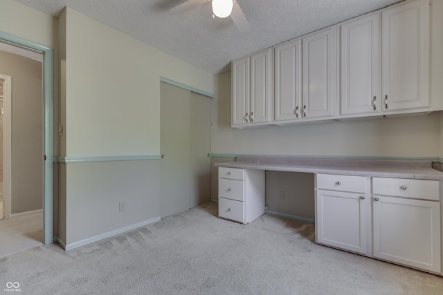 unfurnished office with baseboards, a ceiling fan, a textured ceiling, and light colored carpet