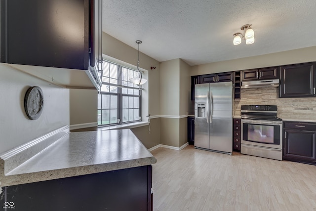 kitchen with light wood-style floors, a textured ceiling, under cabinet range hood, backsplash, and stainless steel appliances