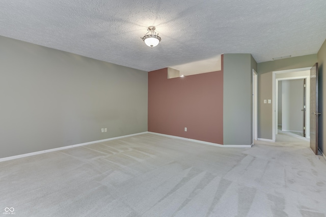 empty room featuring baseboards, light carpet, and a textured ceiling