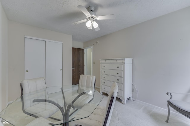 dining room featuring a textured ceiling, ceiling fan, light colored carpet, and baseboards