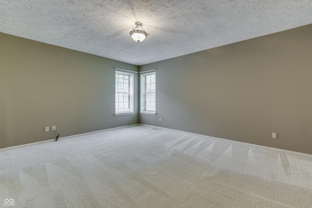 empty room with carpet floors, a textured ceiling, and baseboards