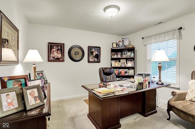 office space with a textured ceiling, baseboards, visible vents, and light carpet