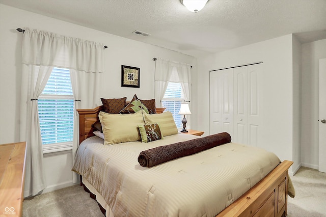 bedroom with visible vents, a closet, multiple windows, and light carpet