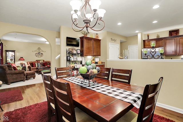 dining room with arched walkways, an inviting chandelier, wood finished floors, and recessed lighting