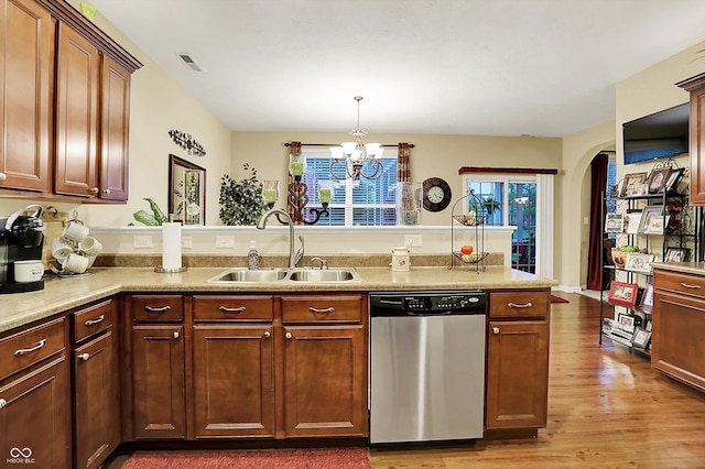 kitchen with a peninsula, wood finished floors, a chandelier, a sink, and dishwasher