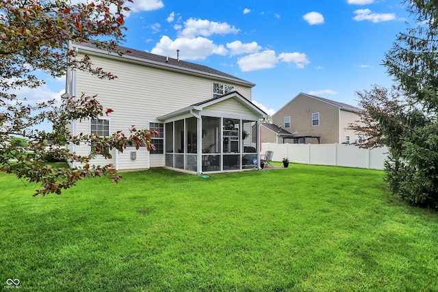 rear view of house featuring a lawn, fence, and a sunroom