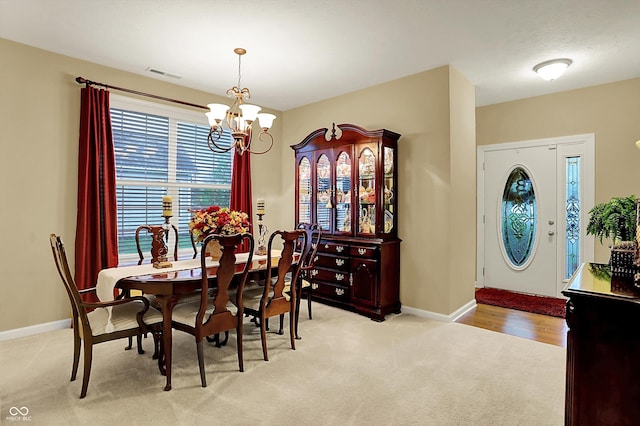 dining room with visible vents, baseboards, a notable chandelier, and light colored carpet