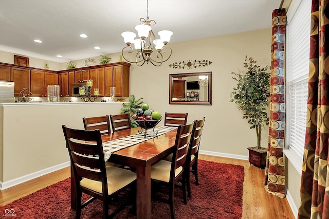 dining space featuring light wood-style floors, baseboards, recessed lighting, and a notable chandelier