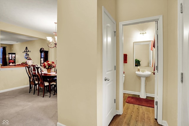 hallway featuring baseboards and a chandelier