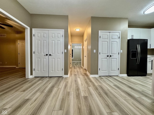 interior space with baseboards, light wood-style flooring, and visible vents