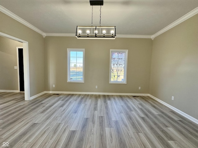 unfurnished dining area featuring crown molding, baseboards, an inviting chandelier, and wood finished floors