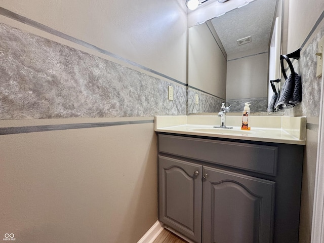 bathroom featuring a textured ceiling, visible vents, and vanity