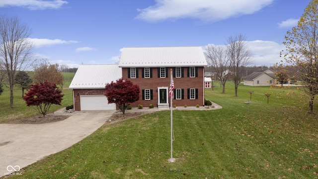 colonial-style house with a garage, metal roof, concrete driveway, a front lawn, and brick siding