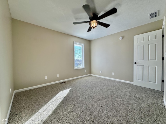 carpeted spare room featuring visible vents, baseboards, and a ceiling fan