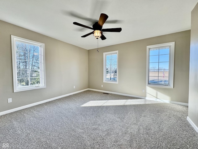 empty room with ceiling fan, carpet floors, baseboards, and visible vents