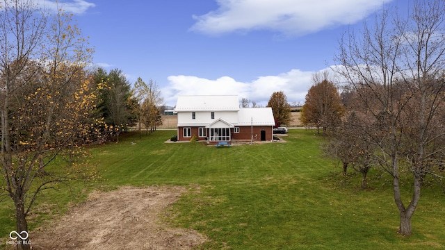 rear view of house featuring a yard, dirt driveway, and metal roof