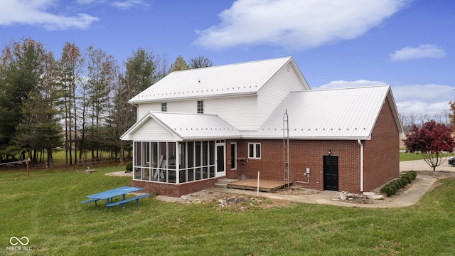 rear view of property with a sunroom, brick siding, metal roof, and a lawn