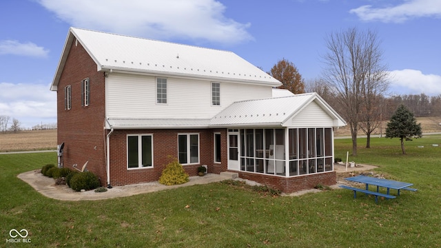 back of property with a sunroom, brick siding, and a lawn