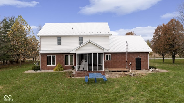 back of house with a yard, metal roof, brick siding, and a sunroom