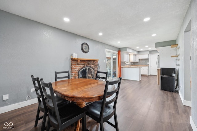 1416 Wellington Ave, Indianapolis, IN 46219 - dining area with recessed lighting, baseboards, a brick fireplace, and dark wood-style flooring