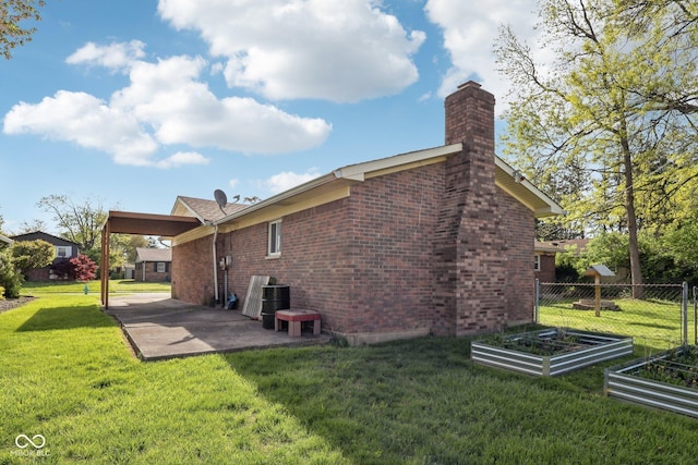 1416 Wellington Ave, Indianapolis, IN 46219 - back of property featuring a garden, a chimney, a lawn, brick siding, and a patio