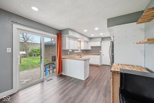 1416 Wellington Ave, Indianapolis, IN 46219 - kitchen with visible vents, a peninsula, black microwave, a textured ceiling, and white cabinets