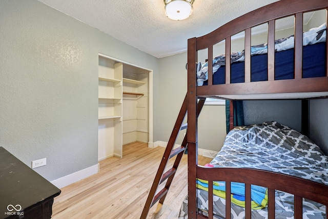 1416 Wellington Ave, Indianapolis, IN 46219 - bedroom with a textured wall, wood finished floors, baseboards, a textured ceiling, and a spacious closet