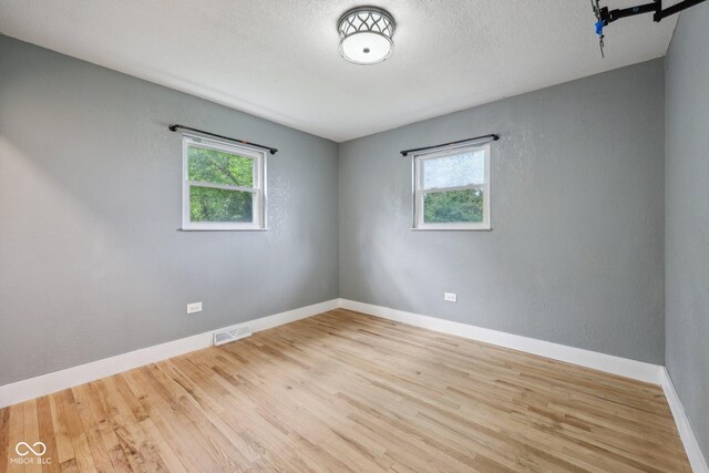 1416 Wellington Ave, Indianapolis, IN 46219 - spare room featuring a healthy amount of sunlight, wood finished floors, and visible vents