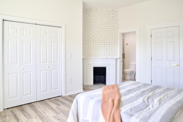 474 N Randolph St, Indianapolis, IN 46201 - bedroom with light wood-style floors, connected bathroom, a closet, and a fireplace