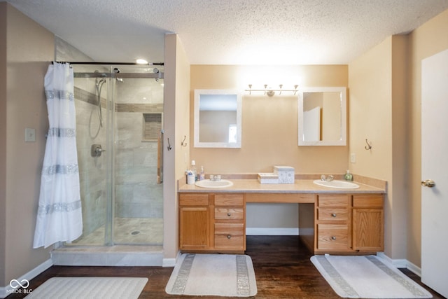 full bath featuring double vanity, a sink, a shower stall, and wood finished floors