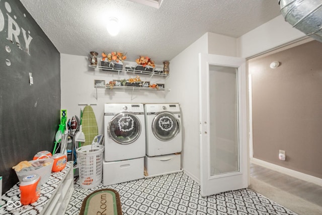clothes washing area with separate washer and dryer, baseboards, laundry area, and a textured ceiling