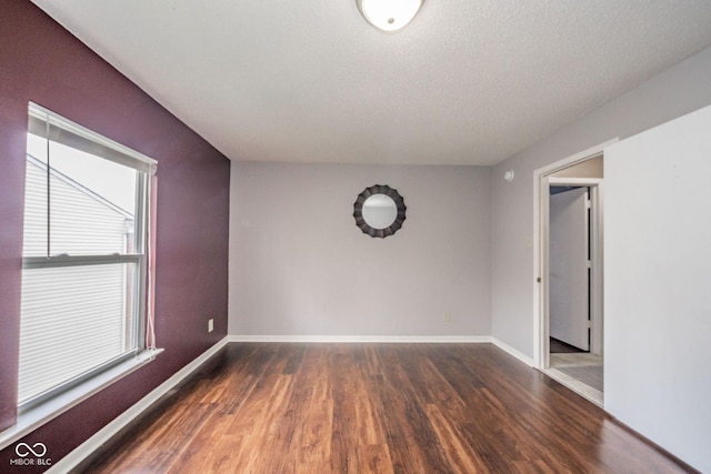 unfurnished room featuring a textured ceiling, baseboards, and wood finished floors
