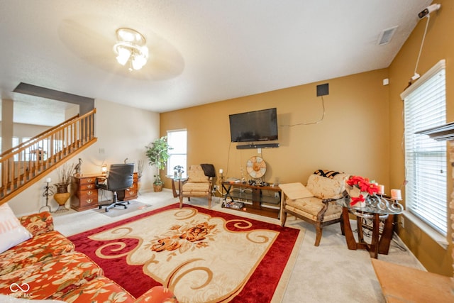living room featuring carpet floors, visible vents, and stairs