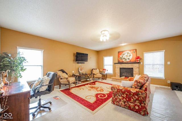 living area featuring carpet floors, baseboards, and a stone fireplace