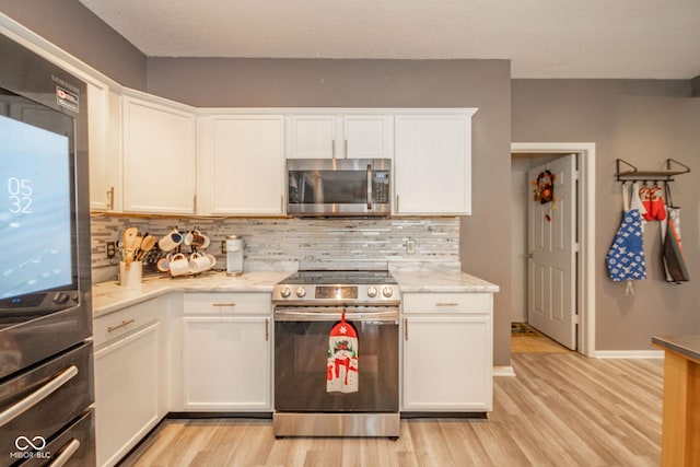 kitchen featuring decorative backsplash, stainless steel appliances, light wood-style flooring, and white cabinetry