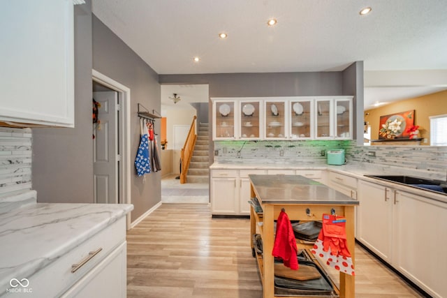 kitchen with white cabinets, recessed lighting, decorative backsplash, and light wood-type flooring