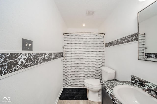 full bath featuring vanity, wood finished floors, curtained shower, toilet, and a wainscoted wall