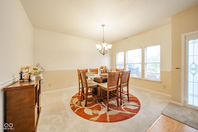 carpeted dining room with plenty of natural light, baseboards, and a chandelier