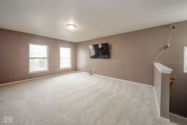 carpeted spare room featuring baseboards and a textured ceiling