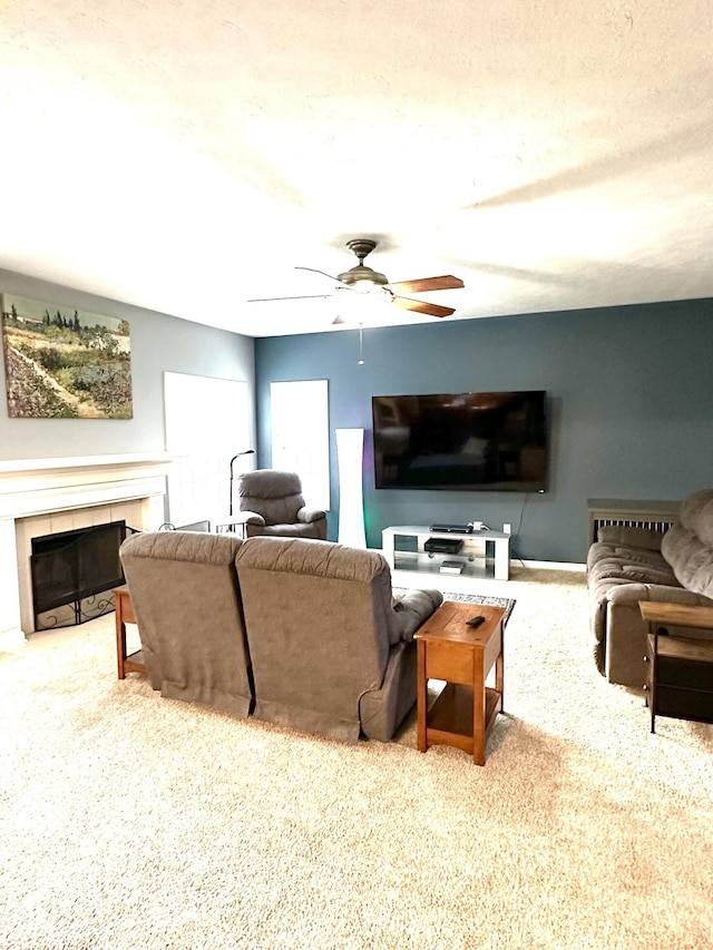 living area featuring carpet floors, ceiling fan, and a tiled fireplace