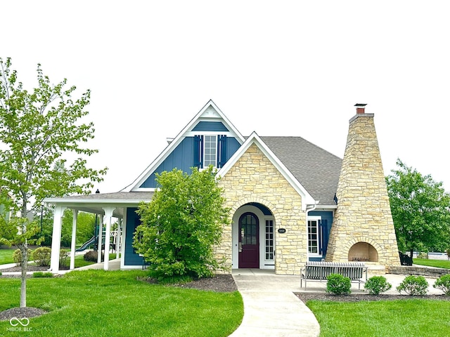 view of front of house with stone siding, a chimney, a front lawn, board and batten siding, and a shingled roof