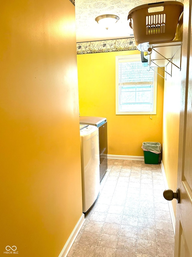 washroom with independent washer and dryer and baseboards