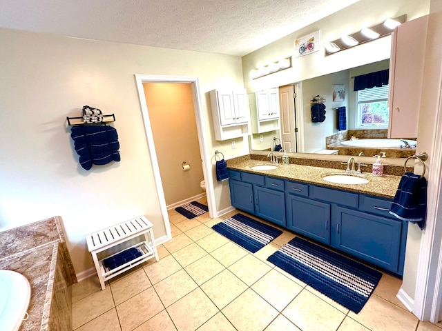 full bathroom featuring double vanity, tile patterned floors, a garden tub, a textured ceiling, and toilet