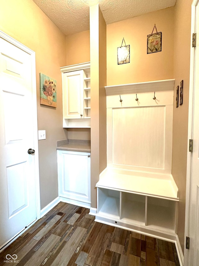 mudroom featuring dark wood finished floors, a textured ceiling, and baseboards