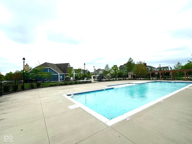 community pool with fence, a patio area, and a residential view
